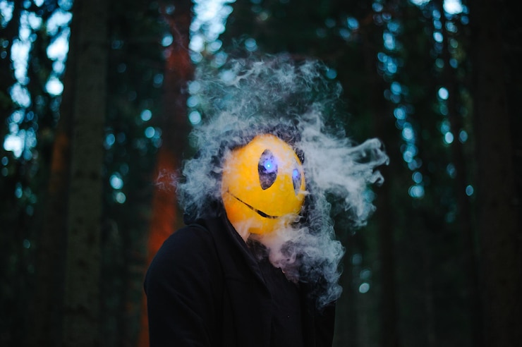 Photo man wearing anthropomorphic face balloon by smoke in forest