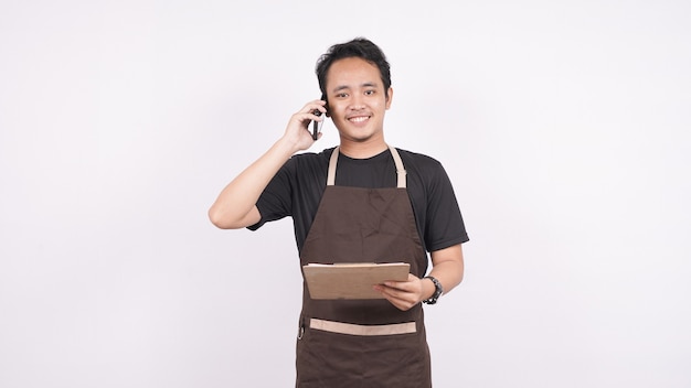 The man wearing the apron stands on a white background isolated on the menu list with phone