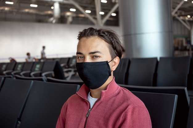 空港で黒い保護マスクを着用している男性。