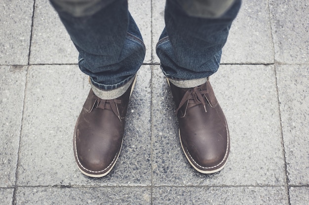 Man wearing blue jeans and a leather boots standing on brick floor