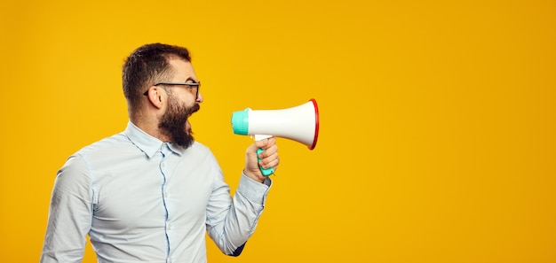 Man wearing blue shirt and eyeglasses standing and screaming in loudspeaker