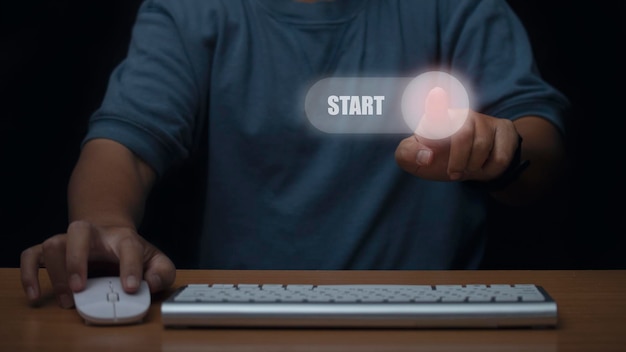 Man wearing blue tshirt press start button to open computer Concept of system start working