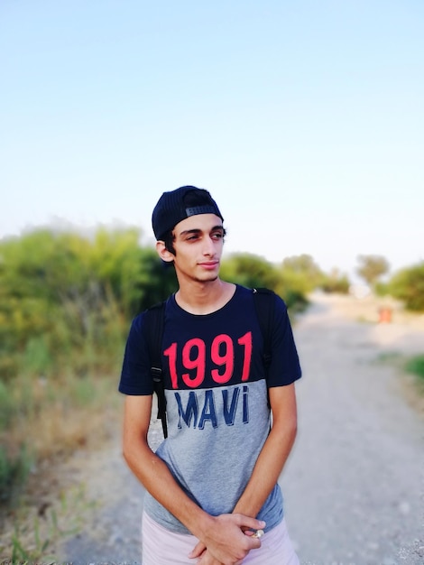 Photo man wearing cap looking away while standing on dirt road