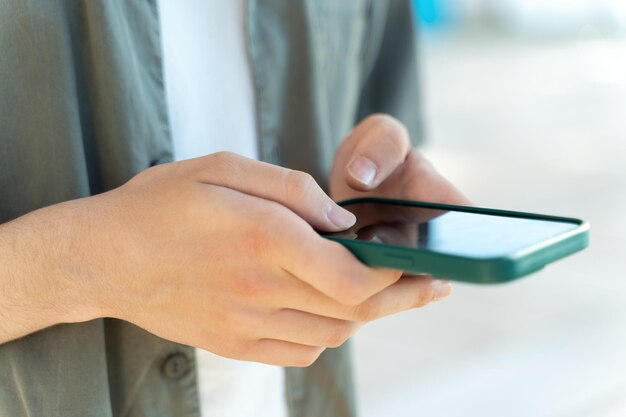 Man wearing casual clothes standing at the street and looking at his smartphone