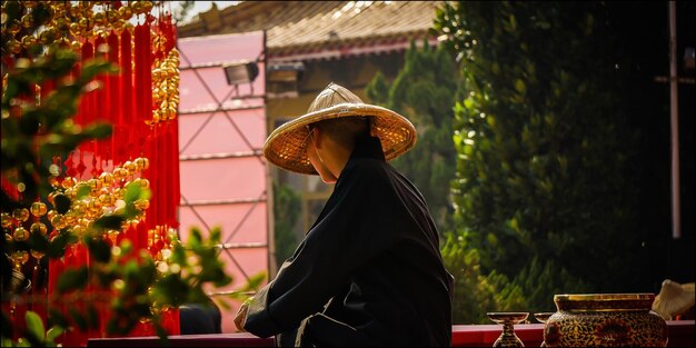 Photo man wearing conical hat while sitting in temple