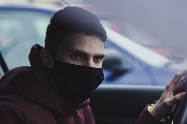 차에 일회용 의료 안면 마스크를 착용하는 남자