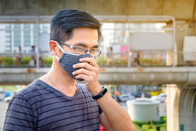 Un uomo che indossa monocolo e maschera nera contro l'inquinamento atmosferico con pm 2,5 a bangkok, thailandia