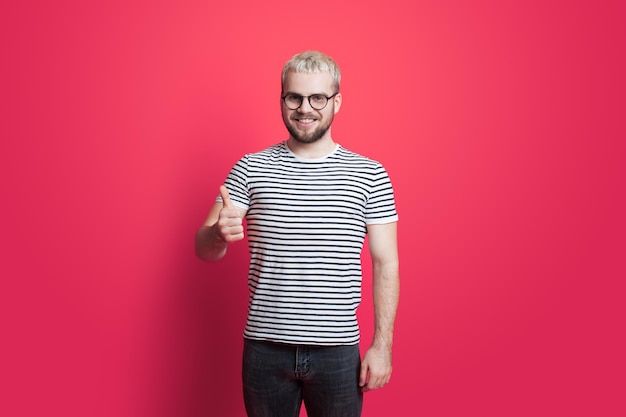 Man wearing eyeglasses isolated over pink background doing thumbs up gesture with hand Approving expression looking at the camera with showing success