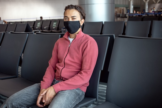공항에서 얼굴 마스크를 착용하는 남자. 테마는 새로운 일반, 코로나 바이러스 및 개인 보호 장치로 이동합니다.
