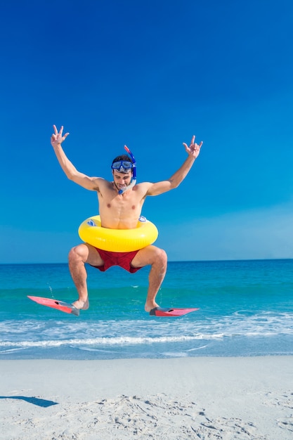 Uomo che indossa pinne e anello di gomma in spiaggia