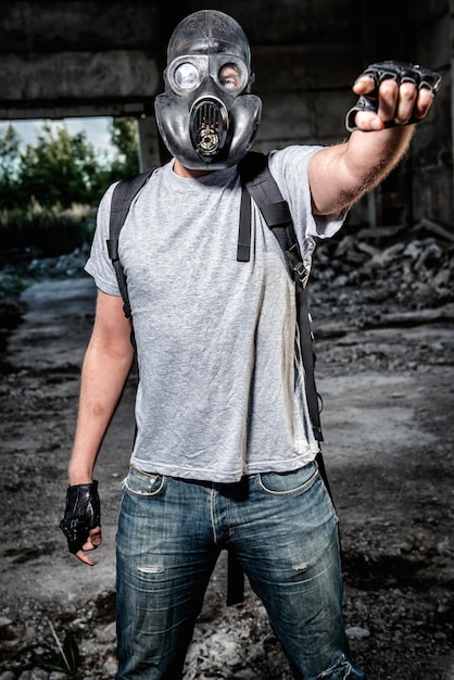 Foto uomo con una maschera antigas in piedi sotto un ponte