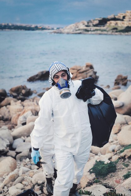 Man wearing gas mask standing on rocks by sea shore