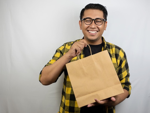 a man wearing glasses holding a paper bag that says " the paper bag ".