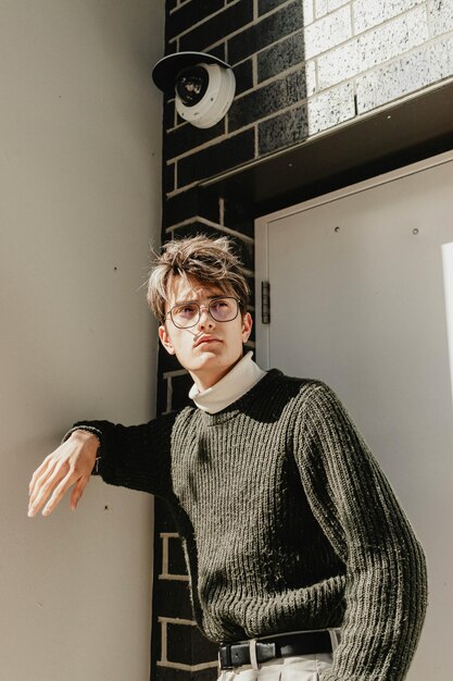 Photo a man wearing glasses leaning against a wall