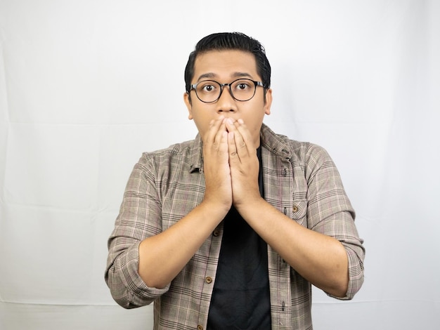 a man wearing glasses and a shirt with his hands in his mouth.