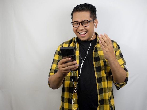 a man wearing glasses and a yellow plaid shirt is smiling and holding a phone in his hand.