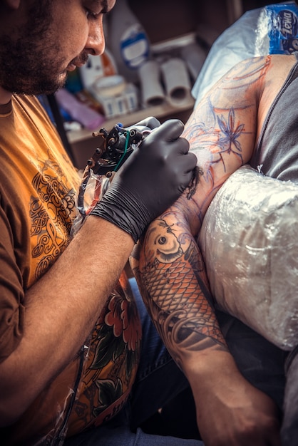 Man wearing gloves making a tattoo in tatoo salon.