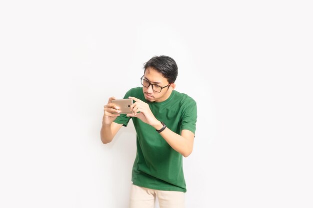 A man wearing a green shirt is using a phone.