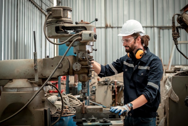 a man wearing a hard hat is working on a machine
