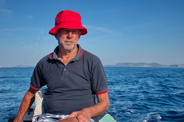 Foto uomo con il cappello seduto sul sedile contro il mare