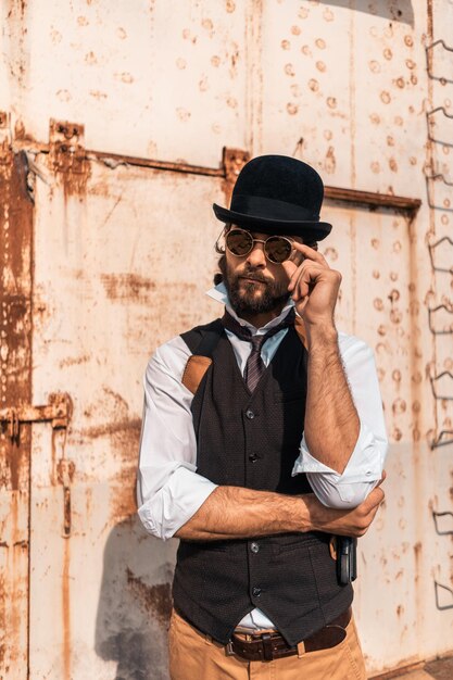 Foto uomo con il cappello in piedi contro il muro