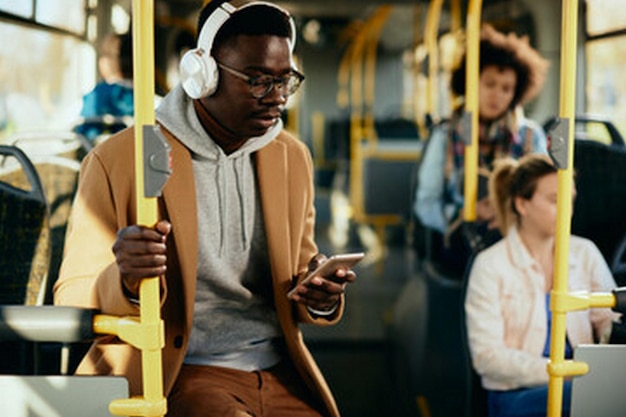 a man wearing headphones and a hoodie is looking at his phone