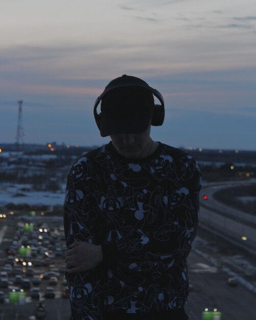 Photo man wearing headphones standing against sky during sunset