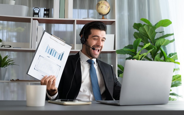 A man wearing a headset holds a clipboard with a chart of cash.