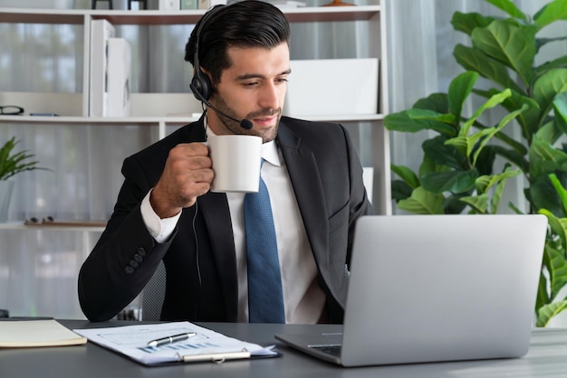 A man wearing a headset is working on a laptop.