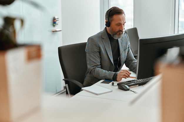 Man wearing headset and sitting at the desk in the office