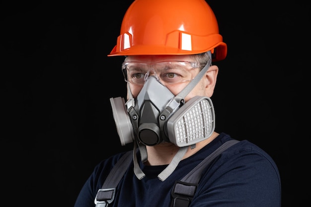 A man wearing a helmet respirator and goggles on a black background