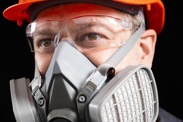 A man wearing a helmet respirator and goggles on a black background