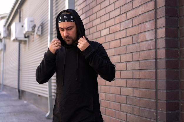 Photo man wearing hooded shirt standing against wall