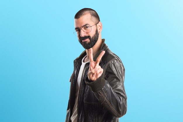 Man wearing a leather jacket doing victory gesture on colorful background