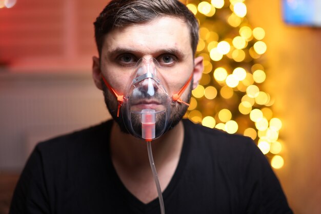 man wearing a lung inhalation mask in front of Christmas lights