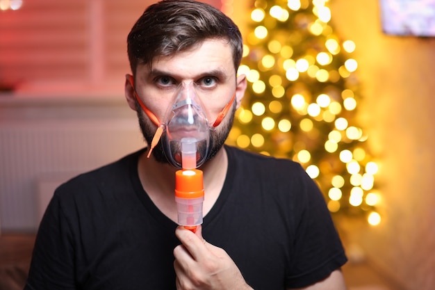 man wearing a lung inhalation mask in front of Christmas lights