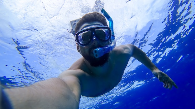 A man wearing a mask and a breathing tube dived into the depths of the red sea and is trying to swim