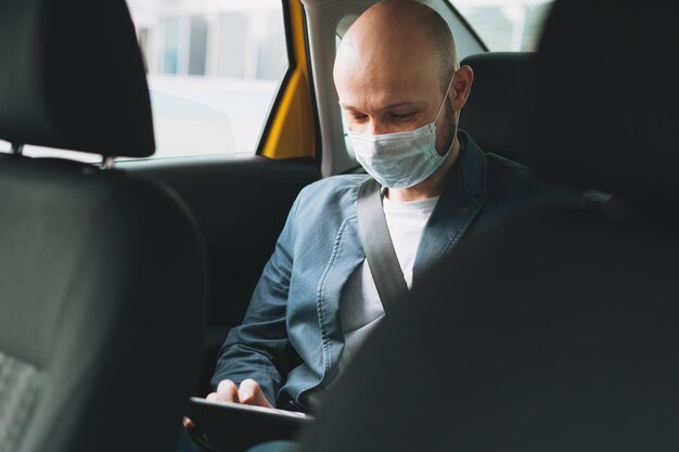 Photo man wearing mask using digital tablet in car