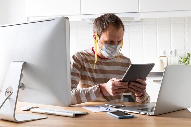 Photo man wearing mask using digital tablet at home