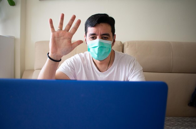 Man wearing a mask with a laptop while self-isolating due to the covid-19 outbreak in spain