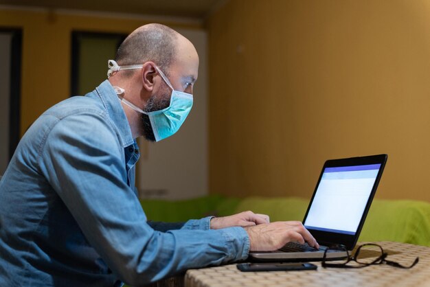 Photo man wearing mask and working from home in isolation from coronavirus