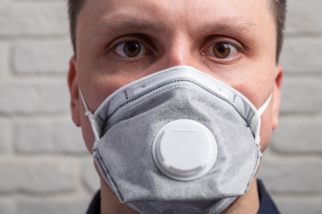 Man wearing a medical mask against the wall
