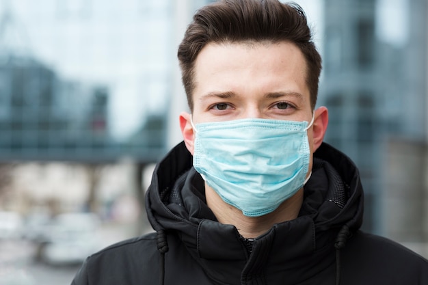 Foto uomo che indossa una maschera medica in città