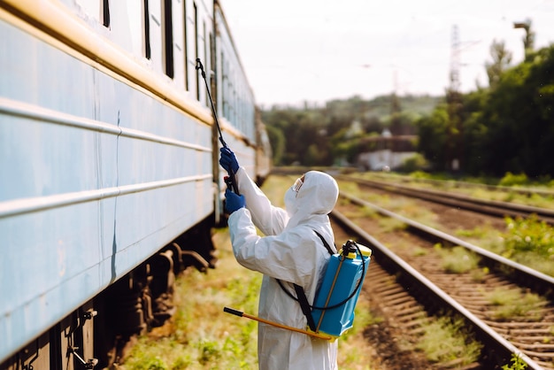 Man wearing protective suit disinfecting public a train