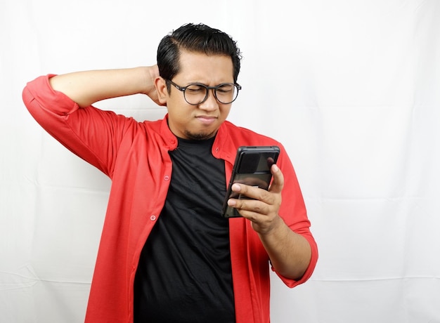 a man wearing a red jacket is holding a phone with his hands behind his head.