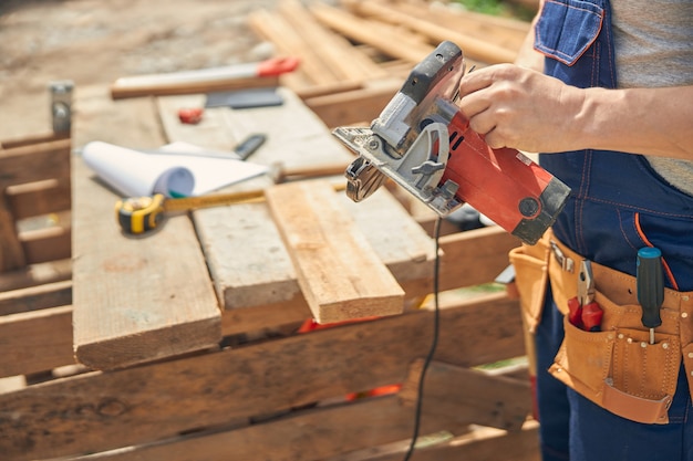 man wearing in safety clothes and holding circular saw