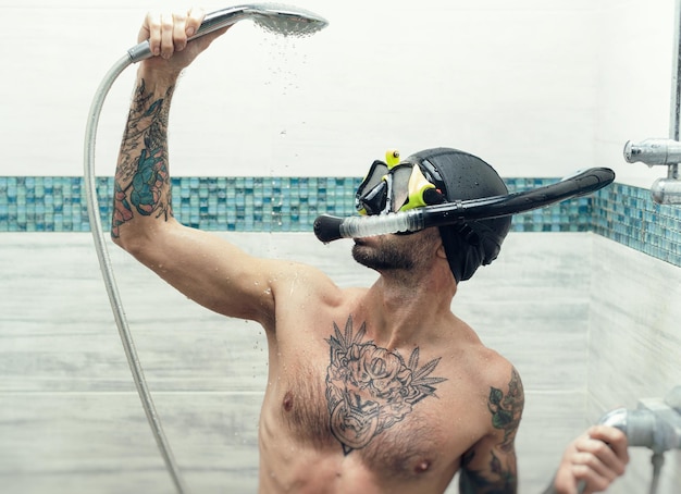 A man wearing a scuba mask in the shower is doused with water