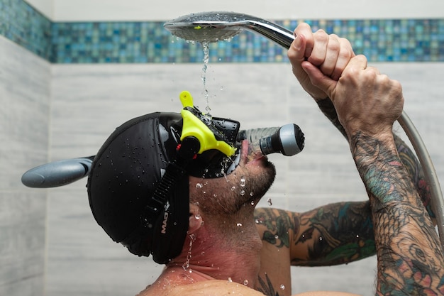 A man wearing a scuba mask in the shower is doused with water