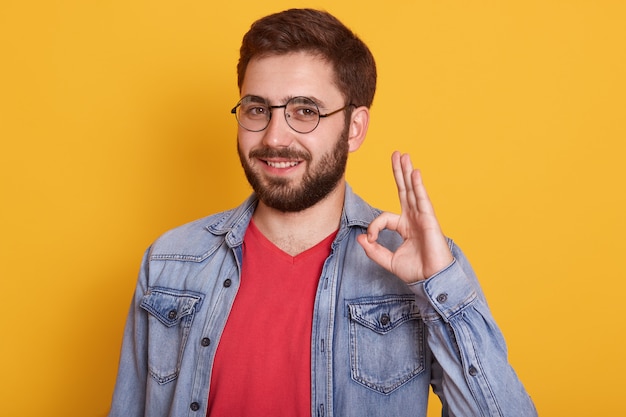 Man wearing stylich clothes making OK sign and looking smiling , guy dressed denim jacket and red t shirt