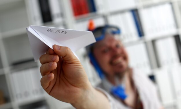 Man wearing suit and tie in goggles and snorkel play with fly paper plane in office closeup Count days to leave annual day off workaholic freedom fun tourism resort idea ticket sale overseas concept